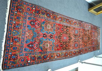 Lot 1239 - North West Persia runner, the madder field with a column of flowerhead medallions enclosed by...