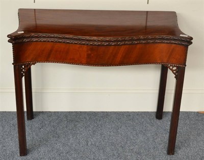 Lot 1313 - A George III mahogany serpentine shaped card table, circa 1800, the flowerhead carved edge and...