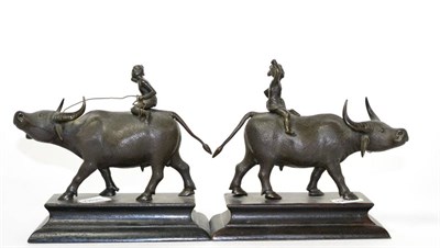 Lot 130 - A pair of bronze figures of water buffaloes with riders, 17cm high