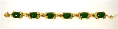 Lot 267 - A nephrite bracelet, formed of six oval cabochon nephrite in yellow leaf frames and spaced by...