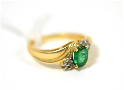 Lot 279 - An emerald and diamond ring, an oval cut emerald in yellow claw settings flanked by clusters of...