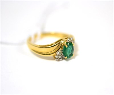 Lot 284 - An emerald and diamond ring, an oval cut emerald in yellow claw settings flanked by clusters of...