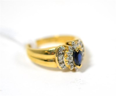 Lot 291 - A sapphire and diamond ring, a marquise cut sapphire in a yellow claw setting within a border...