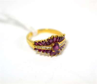 Lot 300 - A ruby and diamond ring, an oval cut ruby in a yellow claw setting, flanked by channel set...