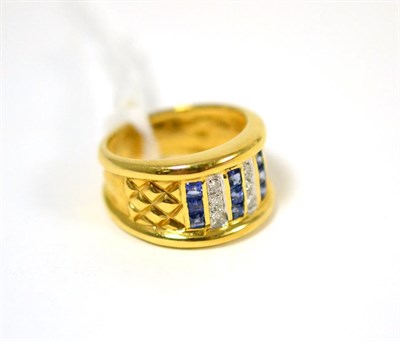 Lot 459 - A sapphire and diamond ring, set with three columns of calibré cut sapphires, spaced by pavé...