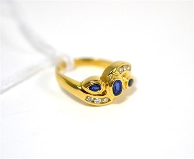 Lot 467 - A sapphire and diamond ring, an oval cut sapphire flanked by pear cut sapphires in yellow...