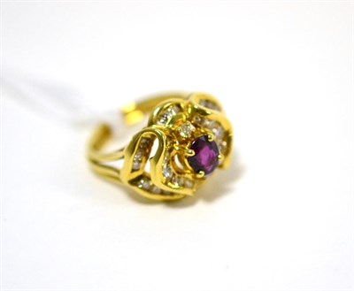 Lot 480 - A garnet and diamond ring, an oval cut garnet in a yellow claw setting within a fancy scroll border