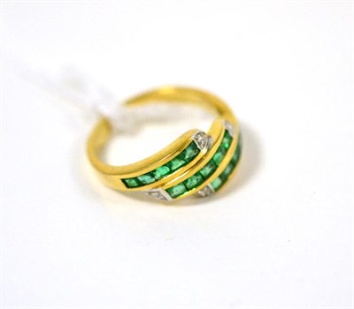 Lot 482 - An emerald and diamond three row ring, set with calibré cut emeralds in yellow channel...