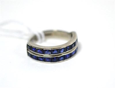 Lot 491 - An 18ct white gold sapphire two row ring, the step cut sapphires in channel settings, on a...