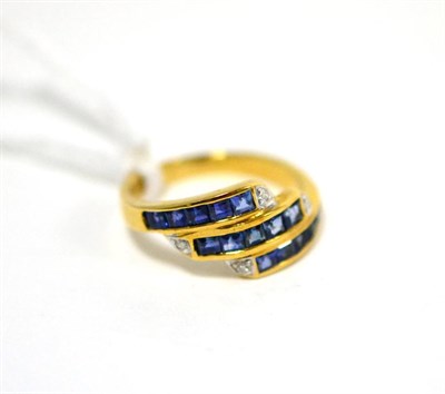 Lot 507 - A sapphire and diamond three row ring, set with calibré cut sapphires in yellow channel...