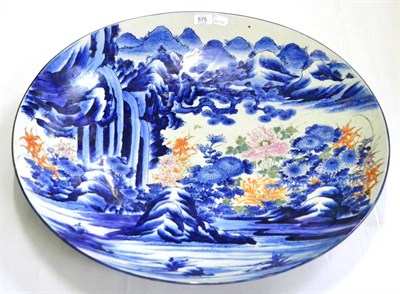 Lot 575 - A large Japanese charger painted with a mountainous and waterfall scene, 69cm diameter