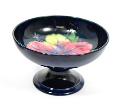 Lot 669 - A Moorcroft blue ground pottery footed bowl ";Hibiscus pattern";, 17cm diameter