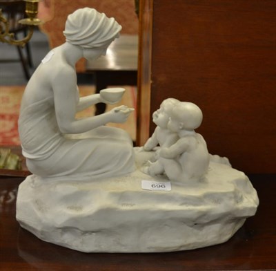 Lot 696 - A Parian bust modelled as a lady kneeling feeding two babies, on a mossy base, 34cm diameter