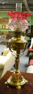 Lot 785 - A late 19th century brass oil lamp with cranberry shade