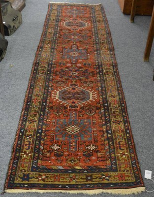 Lot 1214 - A narrow Heriz runner, Iranian Azerbaijan, the brick red field with a column of medallions enclosed