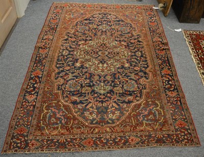 Lot 1234 - A Saroukh rug, West Persia, The deep indigo field of scrolling vines around an ivory stepped...