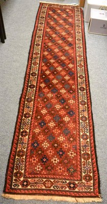 Lot 1247 - A rare narrow Balouch runner, The chestnut field with diagonal columns of stepped güls enclosed by