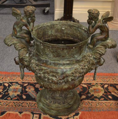 Lot 1318 - A pair of bronzed urns, surmounted by winged figures above lion mask drop handles, 80cm diameter