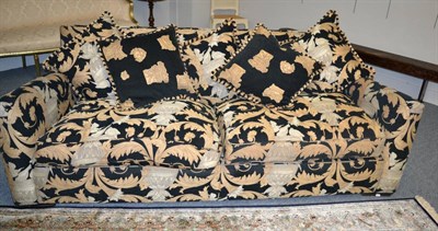 Lot 1389 - A three seater sofa with black and gilt printed fabric, labelled Duresta, with squab and...