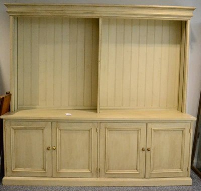 Lot 1401 - A large cream painted pine kitchen dresser, 247cm wide