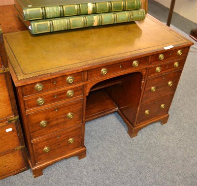 Lot 1576 - A late George III mahogany kneehole desk fitted with an arrangement of nine drawers around an...