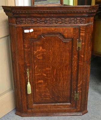 Lot 1626 - #A George III oak hanging corner cupboard with blind fret decorated freize