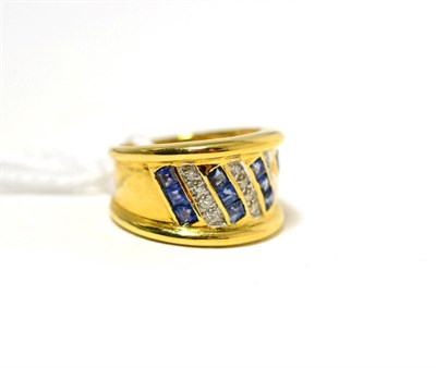 Lot 19 - A sapphire and diamond ring, channel set step cut sapphires spaced by pavé set round brilliant cut