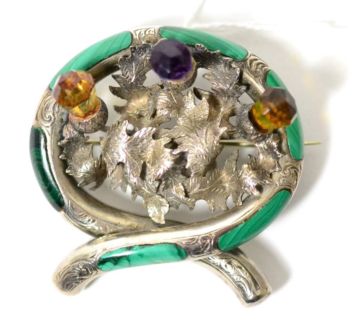 Lot 47 - A Scottish brooch, with a central group of three thistles, the tops set with a faceted amethyst and
