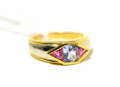 Lot 85 - A sapphire and pink stone ring, an oval cut sapphire flanked by two calibré cut pink stones in...