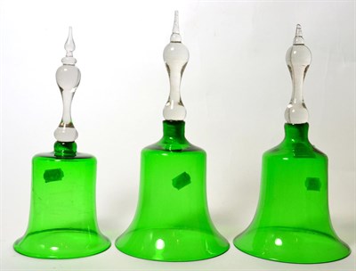 Lot 104 - Three green glass table bells with clear glass handles, tallest 23cm high
