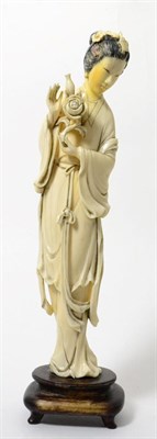 Lot 190 - A Chinese ivory figure of a maiden, 19th century, standing in flowing robes holding a flower,...