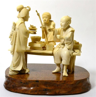 Lot 200 - A Japanese ivory okimono, Meiji period, as a family about a table, 20cm wide, signed to red tablet